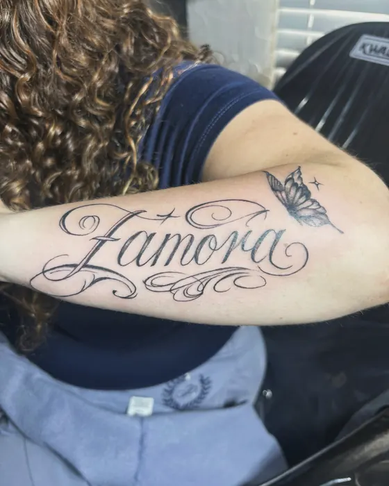 Script name Zamora with a small butterfly on the forearm