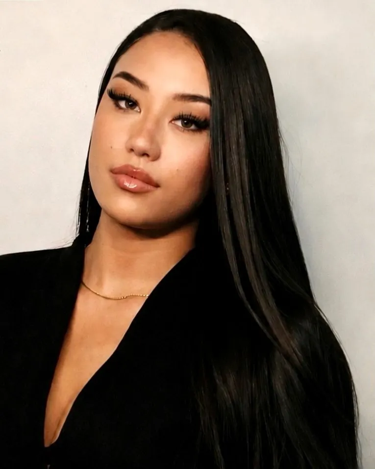 Isabella Kelly, tattoo artist and licensed esthetician, seated in a black suit