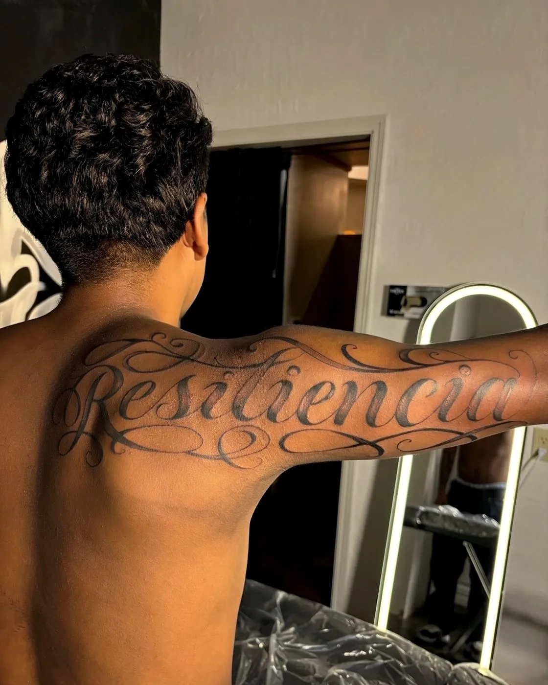 Large custom script lettering tattoo across a client&rsquo;s shoulders and upper back